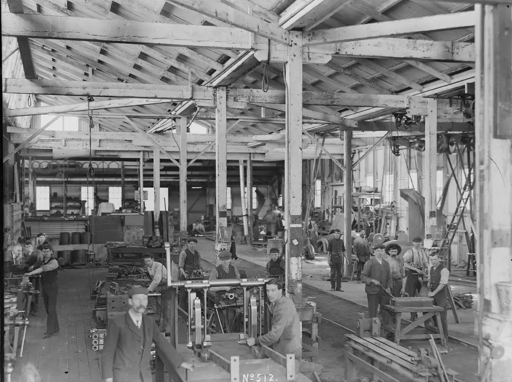 Workers surrounded by heavy machinery inside a locomotive fitting shop.