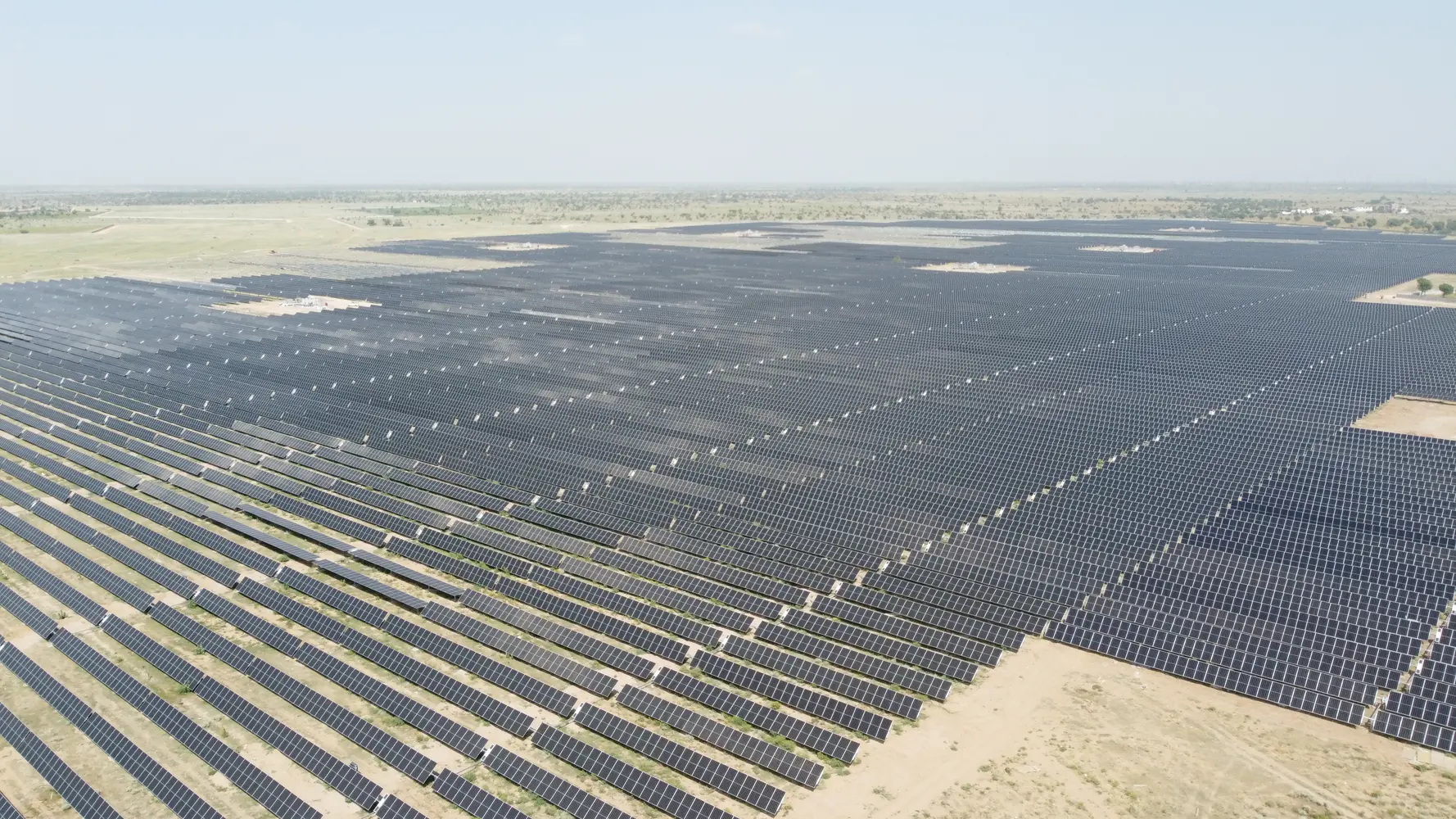 Aerial view of the Bhadla solar power plant, with photovoltaic arrays extending toward the horizon.
